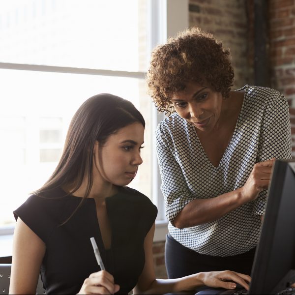 Two Businesswomen Working On Computer In Office